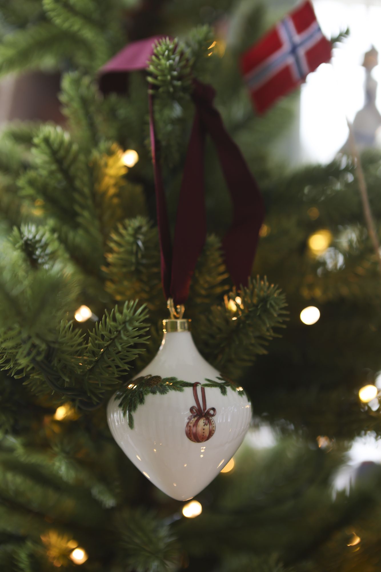 Hvit julekule med rød sløyfe på juletreet